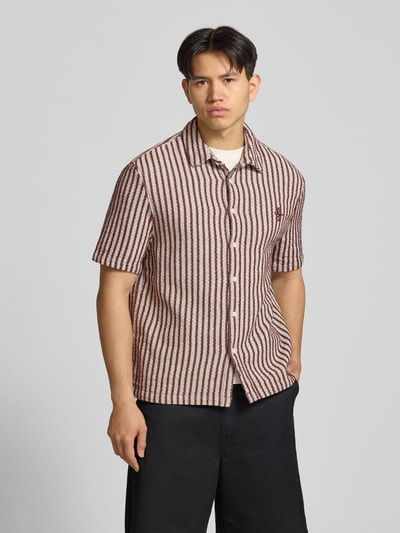 Männermodel trägt Regular Fit Freizeithemd mit Streifenmuster von REVIEW aus Reine Baumwolle, strukturiertes Design, Kentkragen, Knopfleiste, 1/2-Arm, Logo-Stitching, Rot-Beige, Ganzkörperansicht von vorne.