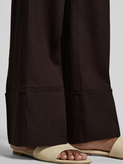 Frauenmodel trägt Hose aus Leinen-Viskose-Mix Modell 'Ottavie' von mbyM, dunkler Farbton, sichtbare Bügelfalten, Nahaufnahme Beinbereich. Damen Hose aus Leinen-Viskose-Mix, Wide Leg, Bügelfalten, Bundweite bei Größe S: 39 cm, Innenbeinlänge bei Größe S: 81 cm.