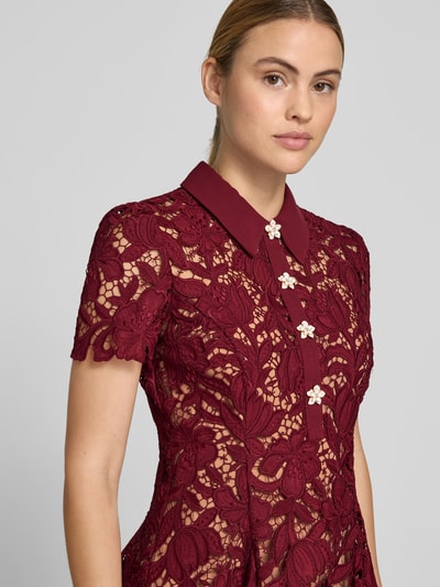 Frauenmodel trägt Minikleid mit Allover-Spitzenbesatz von Self-Portrait in dunklem Rot, florale Spitze, kurzer Ärmel, Nahaufnahme Oberkörper. Taillierte Passform, Umlegekragen, blickdichtes Unterkleid, Maße Größe 36: Länge 88 cm, Brustweite 42 cm, Ärmellänge 20 cm, Taillenweite 35 cm.