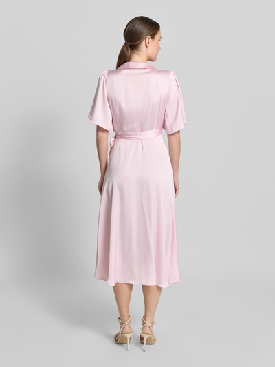Frauenmodel trägt Midikleid in Wickel-Optik Modell 'VIENNA RAVENNA' von Vila aus rosa Satin, taillierter Schnitt, Rückenlänge 125 cm, Ganzkörperansicht Rückansicht.