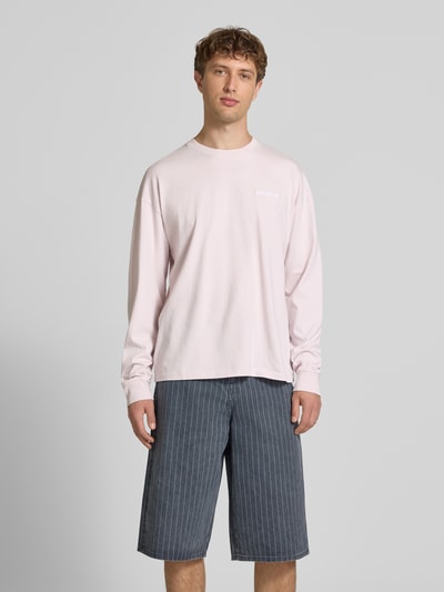Männermodel trägt Oversized Sweatshirt mit Logo-Stitching Modell 'Rusk' von Pegador aus reiner Baumwolle in zartem Rosa, Oversized-Fit, Rückenlänge bei Größe M: 61 cm, Ganzkörperansicht von vorne.