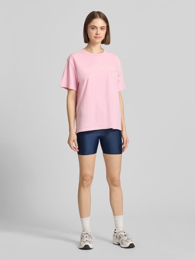 Frauenmodel trägt Slim Fit Shorts mit Logo-Print Modell 'Fairmont' von P.E Nation aus Elastischer-Material-Mix in Dunkelblau, Ganzkörperansicht von vorne.