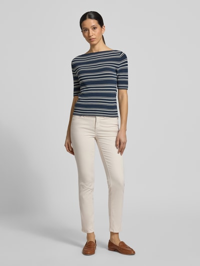 Kobieta nosi spodnie Cropped Hose mit Eingrifftaschen model 'PIPER' von Cambio z bawełny, krój slim fit, beżowe, dł. wewnętrzna nogawki 67 cm, szerokość w rozmiarze 36: 38 cm, wpuszczane kieszenie. Ganzkörperansicht von vorne.