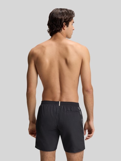 Männermodel trägt Badehose mit Paspelnaht in Kontrastfarbe Modell STARFISH von BOSS, unifarben, Popeline, Ganzkörperansicht Rückansicht.