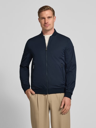 Männermodel trägt Bomberjacke mit Reißverschlusstaschen von Geox in Dunkelblau, Regular-Fit, Stehkragen, Ganzkörperansicht von vorne, Rückenlänge 68 cm, Schulterbreite 46 cm, Brustweite 45 cm, Ärmellänge 64 cm.