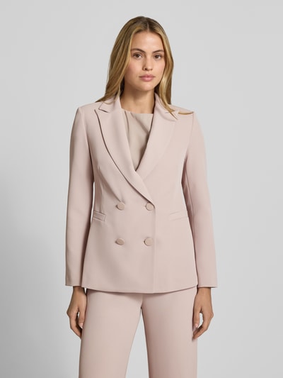 Vrouwenmodel draagt blazer met dubbele knoopsluiting van Rinascimento in lichtroze, reverskraag, getailleerd, paspelzakken, ruglengte maat S 64 cm, frontale close-up bovenlichaam.