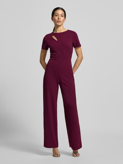 Modelka kobieca nosi Regular Fit Jumpsuit mit Cut-Out od Lipsy, kolor bordowy, krój regular fit, elastyczny materiał, widoczny cut-out, okrągły dekolt, zamek z tyłu, szerokość w rozmiarze 36: 43 cm, długość rękawa: 19 cm, długość całkowita: 146 cm, długość nogawki: 80 cm, pełny widok z przodu.