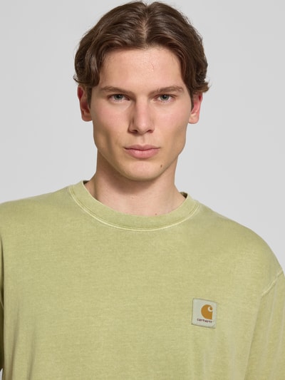 Männermodel trägt Herren T-Shirt mit Label-Detail Modell 'Nelson' von Carhartt Work In Progress, Reine Baumwolle, Rundhalsausschnitt, Relaxed-Fit, Nahaufnahme Oberkörper.