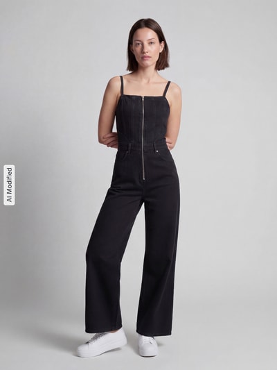 Frauenmodel trägt Regular Fit Jumpsuit aus reiner Baumwolle Modell 'SEAMED' von Levi's® 300 in Schwarz mit sichtbarer Nahtstruktur, Ganzkörperansicht von vorne.