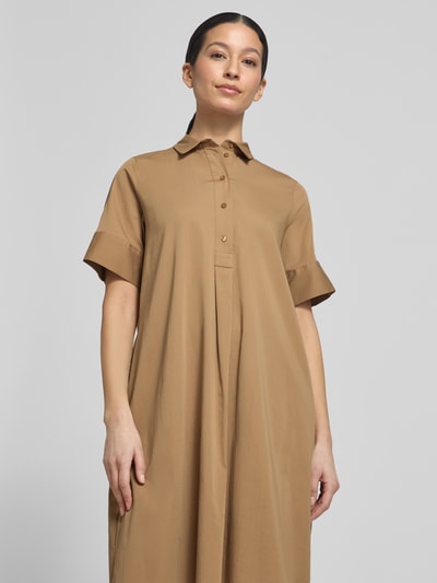 Frauenmodel trägt knielanges Hemdblusenkleid mit Knopfleiste von Milano Italy aus beigem Baumwoll-Mix, gerader Schnitt, Nahaufnahme Oberkörper.