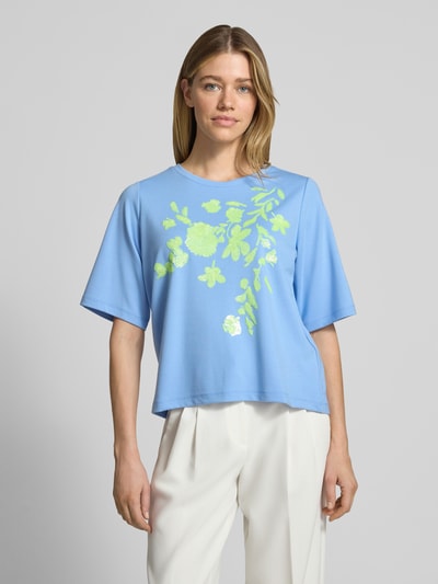 Frauenmodel trägt T-Shirt aus Viskose-Mix mit Paillettenbesatz von Milano Italy in Hellblau mit grünem Motiv-Print, Rundhalsausschnitt, Straight Fit, glatte Textur, Ganzkörperansicht von vorne.