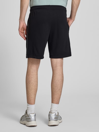 Männermodel trägt schwarze Shorts mit Logo und elastischem Bund von CHAMPION aus Baumwoll-Mix, Regular Fit, Rückansicht Ganzkörperansicht.