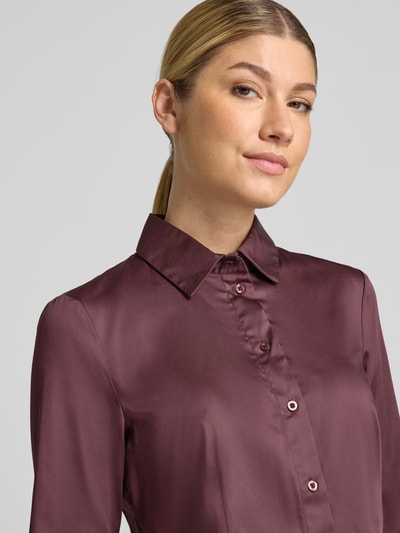 Frauenmodel trägt Hemdbluse aus Baumwoll-Mix von Christian Berg Woman in Dunkelrot, glatte Oberfläche, tailliert, Nahaufnahme Oberkörper. Baumwoll-Mix mit Stretch-Anteil, langärmeliges Design, 1-Knopf-Manschetten, Rückenlänge 64 cm, Ärmellänge 61 cm.