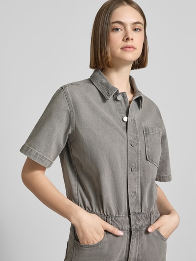 Frauenmodel trägt Regular Fit Playsuit in Denim-Optik Modell 'Fillipa' von JJXX aus Reine Baumwolle mit Brusttasche und Knopfleiste, Kurzärmelig, 5-Pocket-Design, graue mittelhelle Farbe, glatte Struktur, Nahaufnahme Oberkörper.