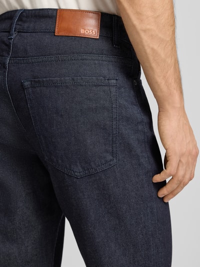 Mężczyzna nosi Jeans im 5-Pocket-Design Modell "Re.Maine" od BOSS Orange, ciemnoniebieski bawełniany materiał z domieszką stretchu, detal tylnych kieszeni, zdjęcie w zbliżeniu na biodro