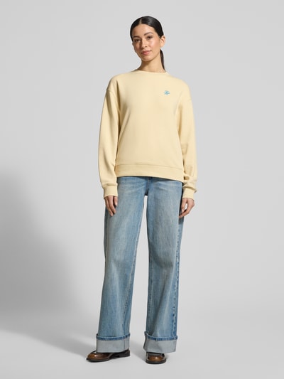 Frauenmodel trägt Regular Fit Sweatshirt aus Baumwoll-Mix von Tommy Hilfiger, Optik: Unifarben, Logo-Detail, Rundhals, Langarm, gerippte Abschlüsse, Materialverarbeitung: Sweat, Farbe Beige, glatte Textur, Ganzkörperansicht von vorne.