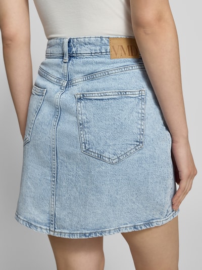 Frauenmodel trägt Regular Fit Jeansrock aus Baumwoll-Mix Modell 'TESSA' von Vero Moda in heller Denim-Optik mit Label Patch, Ganzkörperansicht Rückansicht.