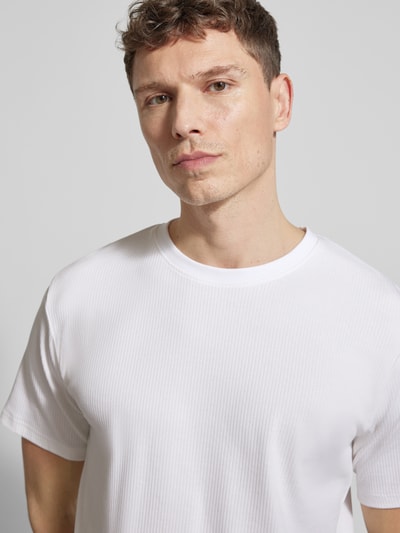 Männermodel trägt Regular Fit T-Shirt aus Baumwoll-Mix Modell 'SPENCER' von SELECTED HOMME, weiß, gestreift strukturiert, Nahaufnahme Oberkörper.