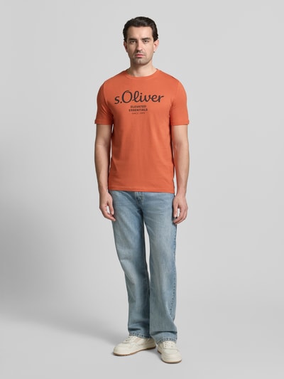 Männermodel trägt Regular Fit T-Shirt aus reiner Baumwolle von s.Oliver RED LABEL in Orange, unifarbenes Jersey, Label Print, Ganzkörperansicht von vorne.
