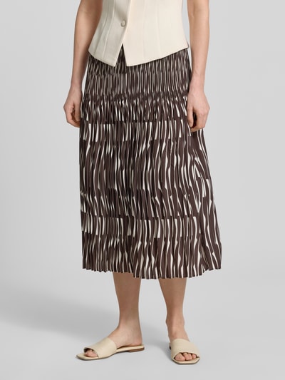 Vrouwenmodel draagt midirok in plooienlook model 'Ribane' van OPUS in licht A-lijn met elastische band en tunnelkoord, totaal bruine tinten, detailopname onderlichaam. Context: dames midirok met bandwijdte maat 36: 35 cm, totale lengte maat 36: 82 cm.