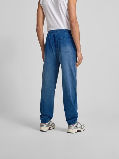 Männermodel trägt Sweathose mit elastischem Bund von Diesel aus reiner Baumwolle, lockerer Schnitt, Gesäßtasche, Ganzkörperansicht Rückansicht.