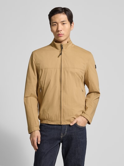 Mannenmodel draagt heren jack met recht model van katoenmix met stretch, opstaande kraag, ritszakken, ritssluiting, model 'Calvin' van Brax, effen lichtbruin, voorkant, close-up bovenlichaam.