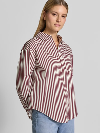 Frauenmodel trägt Regular Fit Hemdbluse mit Brusttasche Modell 'FONTANA' von Mango, aus Baumwoll-Mix, Weiß mit bordeauxroten Streifen, Hemdblusenkragen, Rückenlänge und Ärmellänge bei Größe S, Nahaufnahme Oberkörper.