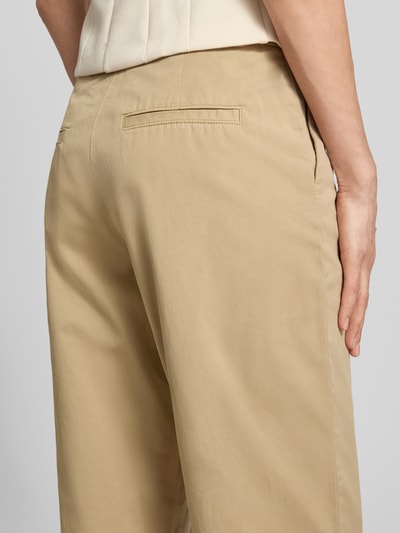 Frauenmodel trägt Chino mit Paspeltaschen am Gesäß von Jake*s Casual in Beige, Relaxed-Fit, glatte Textur, Nahaufnahme Rückansicht. Bundweite 37 cm, Innenbeinlänge 68 cm, verkürzte Passform, mit Eingrifftaschen.