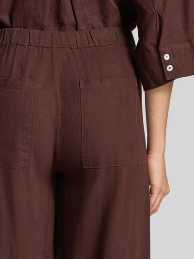 Frauenmodel trägt Stoffhose aus Leinen-Viskose-Mix Modell 'Lava' von FREE/QUENT, braune Farbe, sichtbarer Elastikbund, Relaxed-Fit, Detailaufnahme Rückansicht, Damen Stoffhose, Bundweite bei Größe S 37 cm, Innenbeinlänge 66 cm.