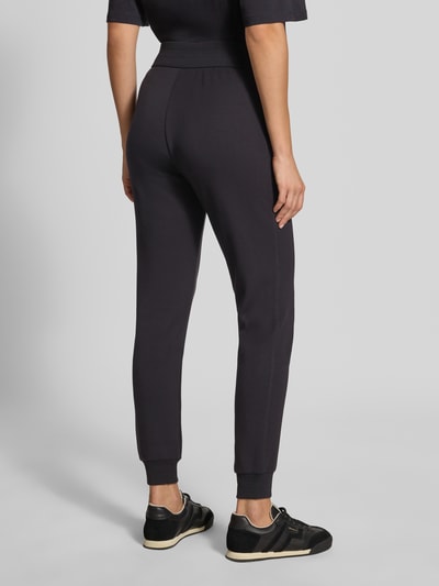 Kobieta nosi Slim Fit Sweatpants aus Viskose-Mix od Armani Exchange w kolorze ciemnym, elastyczne wykończenia, pas, długość wewnętrzna nogawki 74 cm w rozmiarze S, mieszanka wiskozy, krój slim fit, spodnie dresowe, widok całej sylwetki z tyłu.