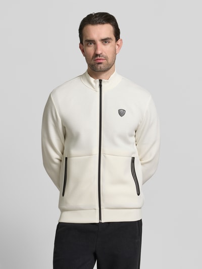 Männermodel trägt Sweatjacke mit Reißverschluss von EA7 Emporio Armani in Creme, Regular Fit, gerippte Abschlüsse, Ganzkörperansicht von vorne.