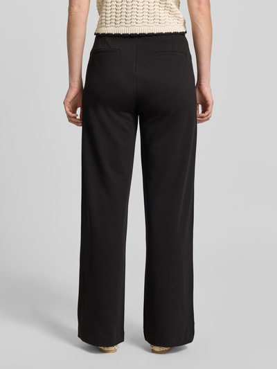 Frauenmodel trägt Wide Fit Stoffhose mit Viskose-Anteil Modell 'Nanni' von FREE/QUENT, Elastischer-Material-Mix, schwarze Farbe, Ganzkörperansicht Rückansicht, Bundweite bei Größe M 41 cm, Innenbeinlänge 82 cm.