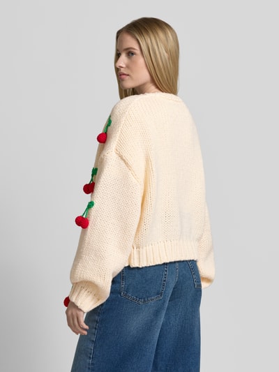 Frauenmodel trägt Oversized Strickjacke mit Zier-Applikationen von Apricot, Grobstrick, cremefarben, Rückenlänge 55 cm, Ganzkörperansicht Rückansicht.