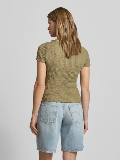 Frauenmodel trägt Slim Fit T-Shirt mit Strukturmuster Modell 'Alora' von Noisy May, olivgrün, elastisch, kurzärmelig, Ganzkörperansicht Rückansicht.