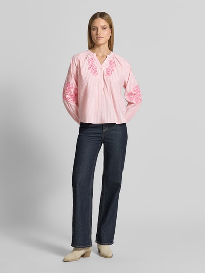 Kobiece modelka nosi Regular Fit Bluse mit floralem Stitching od Emily Van den Bergh, bluzka z bawełny, krój regular fit, kwiatowy haft, dekolt z lamówką, z długim rękawem, różowe i białe pionowe paski, gładka faktura, długość tyłu w rozmiarze 36: 58 cm, długość rękawów w rozmiarze 36: 47 cm, gładkie zakończenia rękawów, ganzkörperansicht von vorne.