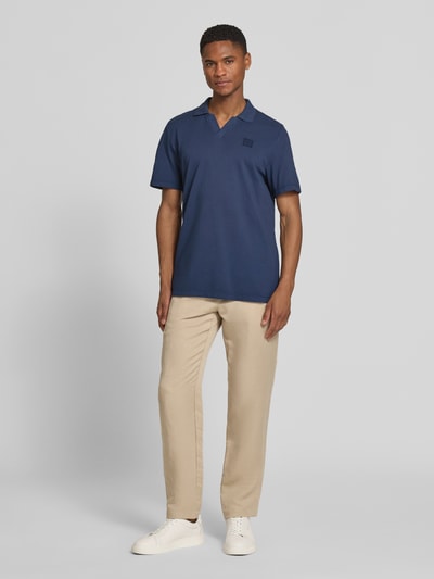 Männermodel trägt Regular Fit Poloshirt aus reiner Baumwolle von s.Oliver RED LABEL in Dunkelblau, unifarben, Ganzkörperansicht von vorne.