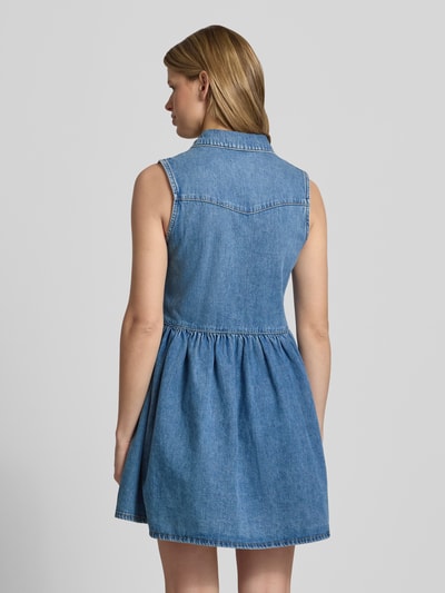 Männermodel trägt Tailliert Jeanskleid aus reiner Baumwolle Modell 'CYRUS' von Only, Optik Denim, krój slim fit, mini, V-dekolt, bez rękawów, prosta krawędź, zdjęcie całej sylwetki z tyłu.