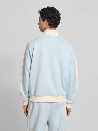 Männermodel trägt Regular Fit Sweatjacke mit Logo-Stitching von KARL KANI in Hellblau und Creme, Elastischer-Material-Mix, Rückenansicht.