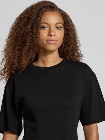 Modelka prezentuje damski t-shirt z bawełny, prosty krój, okrągły dekolt, marszczenia model 'MALLE' od Topshop, zbliżenie na górę.