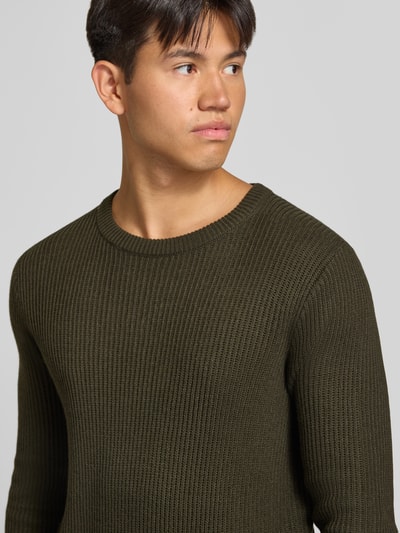 Männermodel trägt Strickpullover mit Rundhalsausschnitt Modell 'PANNEL' von JACK & JONES, Olivgrün, fein gerippte Struktur, Nahaufnahme Oberkörper, Material-Mix mit Baumwoll-Anteil, eng anliegender Schnitt.