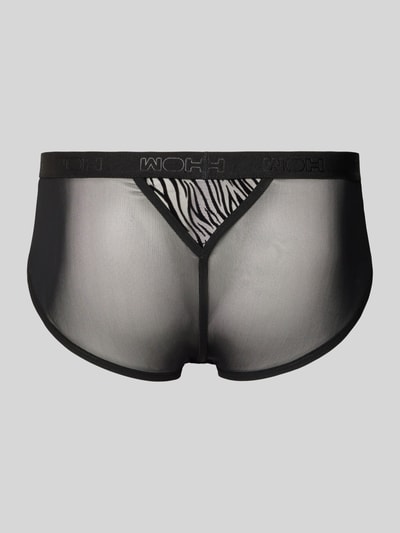 Männermodel trägt Briefs mit Cut Out Modell 'Personal Allure' von WOH, schwarzer Material-Mix, semitransparent, Logo-Bund, Ganzkörperansicht Rückansicht.