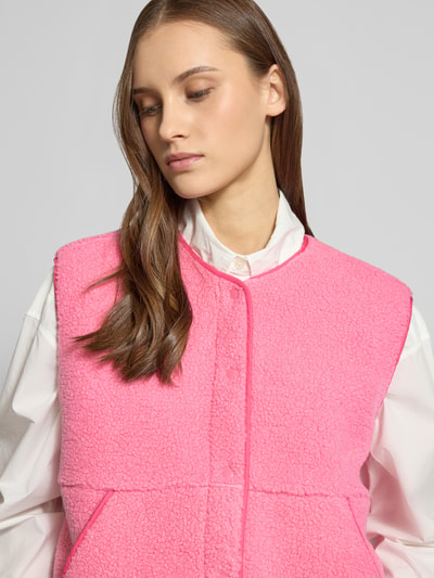 Frauenmodel trägt Relaxed Fit Weste in Teddy-Optik Modell 'Vera' von JJXX in kräftigem Pink, sichtbare Knopfleiste, Rundhalsausschnitt, und Eingrifftaschen, Nahaufnahme Oberkörper. Rückenlänge 54 cm, Schulterbreite 45 cm, Brustweite 58 cm bei Größe S.