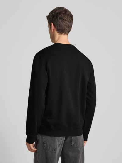Męski model nosi czarne Sweatshirt mit Label-Detail Modell 'Dem' od HUGO z bawełny, luźny krój, widok całej sylwetki od tyłu.