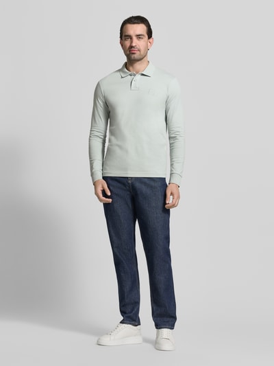 Männermodel trägt Slim Fit Poloshirt aus Baumwoll-Mix Modell 'PASSERBY' von BOSS Orange in Hellgrün, unifarben, Ganzkörperansicht von vorne.