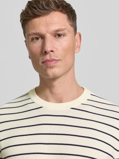 Männermodel trägt T-Shirt mit geripptem Rundhalsausschnitt von MCNEAL, cremefarben mit schwarzen Streifen, Regular Fit, Nahaufnahme Oberkörper.
