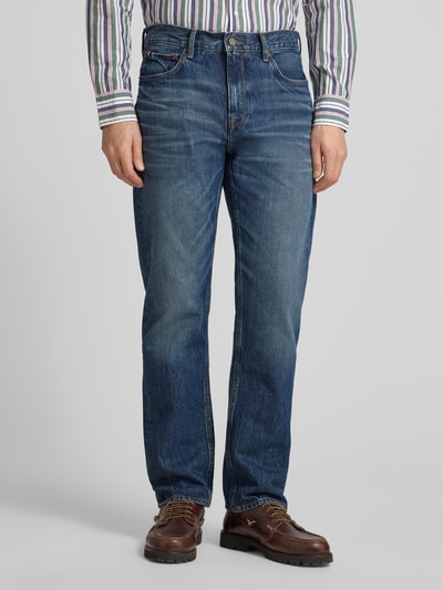 Męski model nosi Straight Fit Jeans aus reiner Baumwolle Modell 'DOVER' von Tommy Hilfiger w kolorze ciemnego denimu, widok z przodu, ujęcie całej sylwetki.