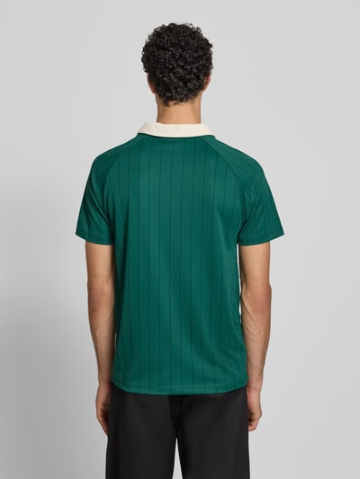 Männermodel trägt Regular Fit T-Shirt mit Umlegekragen von KARL KANI, grün mit Logo-Stitching, Rückenlänge 67 cm, Ganzkörperansicht Rückansicht.