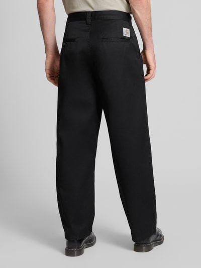 Männermodel trägt Chino mit Gesäßtaschen Modell 'BRADY' von Carhartt Work In Progress, lockerer Schnitt, schwarze Baumwollmischung, Ganzkörperansicht Rückansicht.