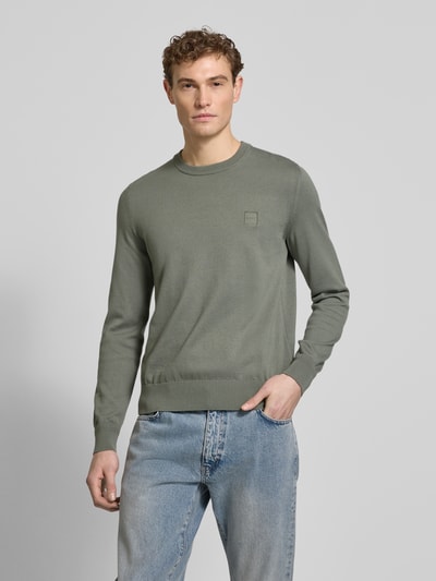 Männermodel trägt Regular Fit Strickpullover aus Baumwoll-Kaschmir-Mix Modell 'KANOVANO_S' von BOSS Orange in unifarbenem Grün, Ganzkörperansicht von vorne.
