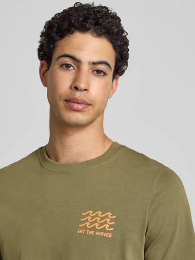 Männermodel trägt T-Shirt mit Motiv-Print Modell 'SUN ISLAND' von Blend in Olivegrün aus Baumwolle, Nahaufnahme Oberkörper.